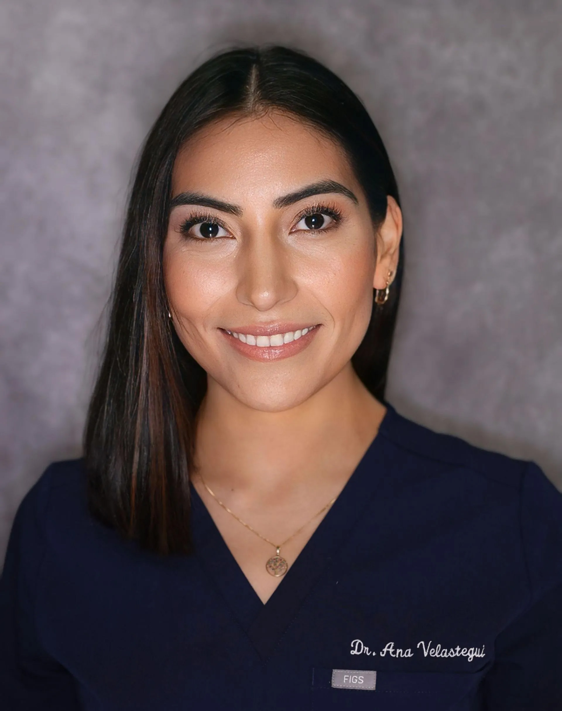 A woman in a white lab coat, smiling at the camera.
