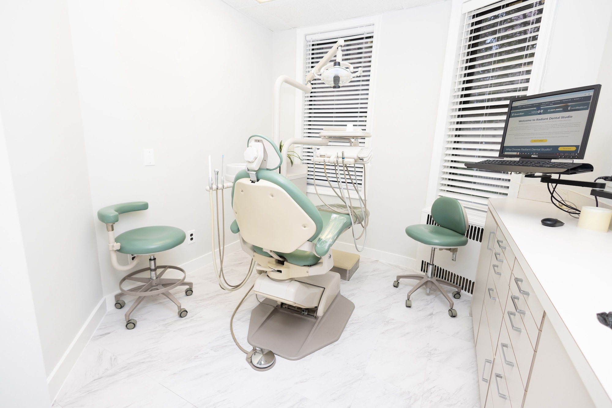 Dental office interior with dental chair, treatment table, and equipment.