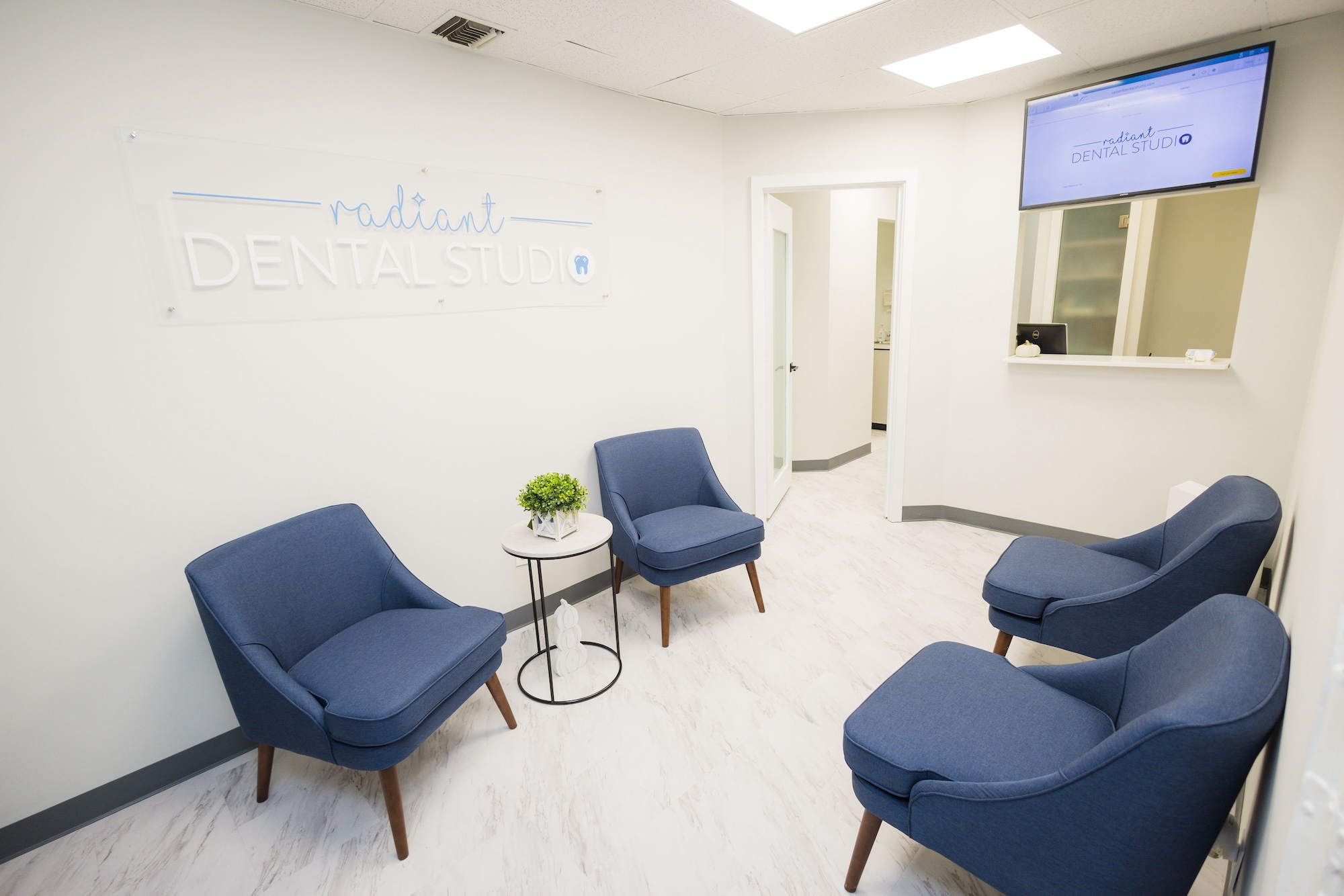 The image depicts an interior space, likely a dental studio or office, with modern furnishings and a welcoming atmosphere.