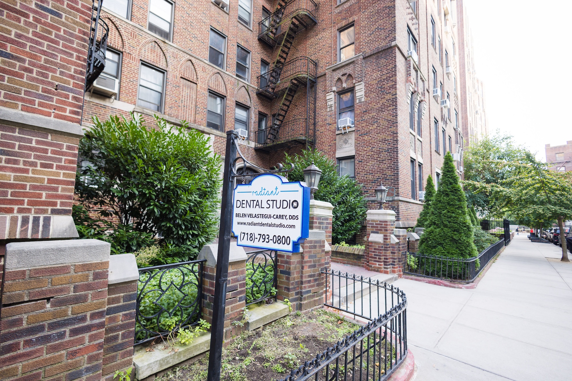 A sign for a real estate listing in front of a multi-story apartment building.