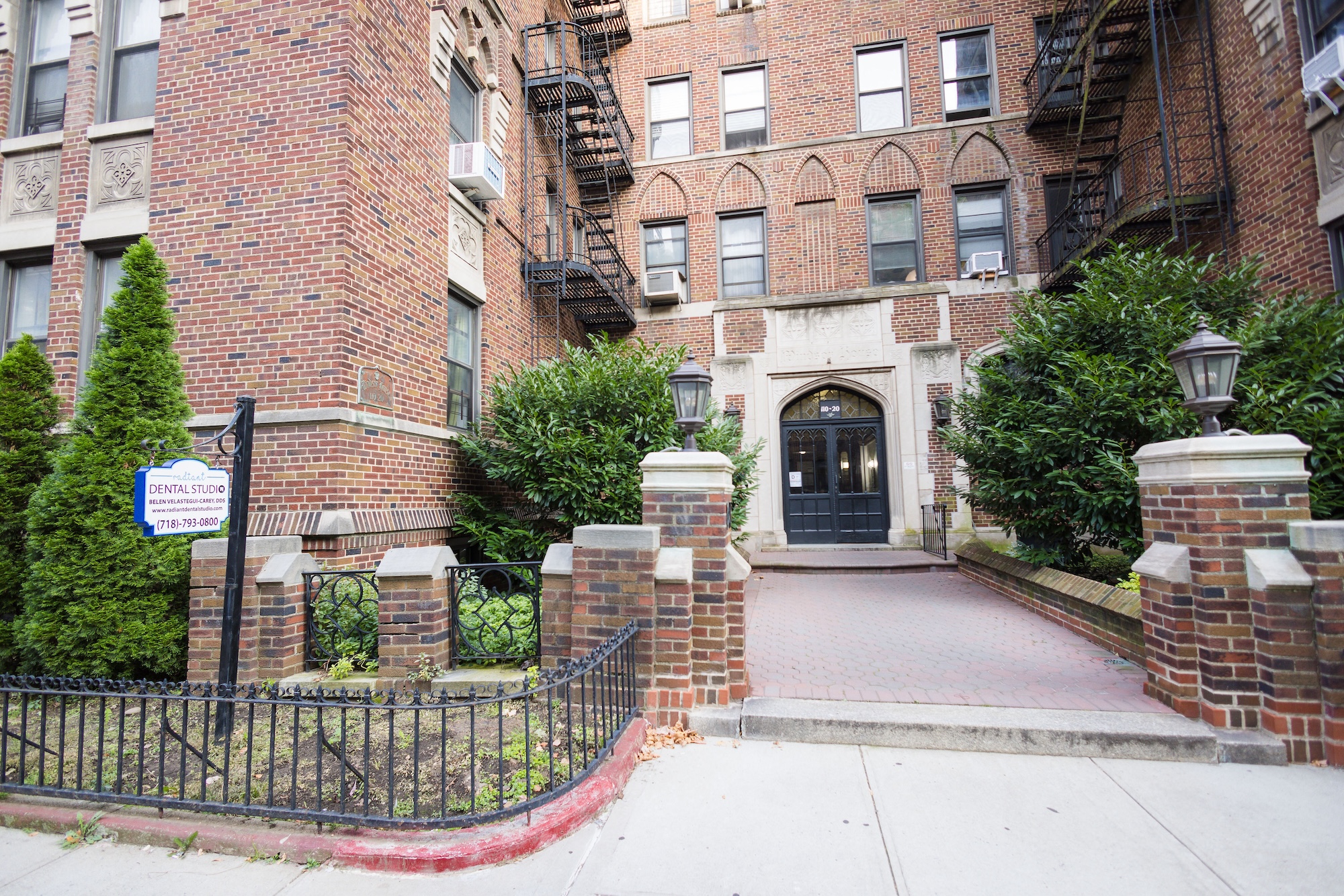 The image depicts a residential building with an entrance, featuring a sign that reads  The Apartments  and a plaque indicating it s a co-op.