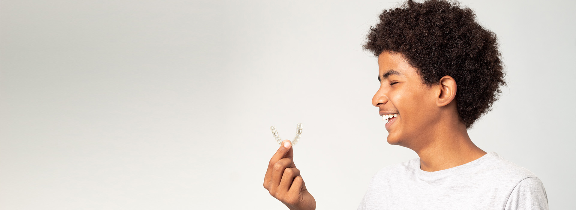 The image shows a person holding a flower with a joyful expression, set against a blurred background.