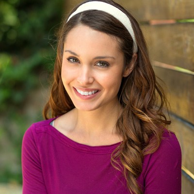 A young woman with long hair, smiling and posing for a portrait.