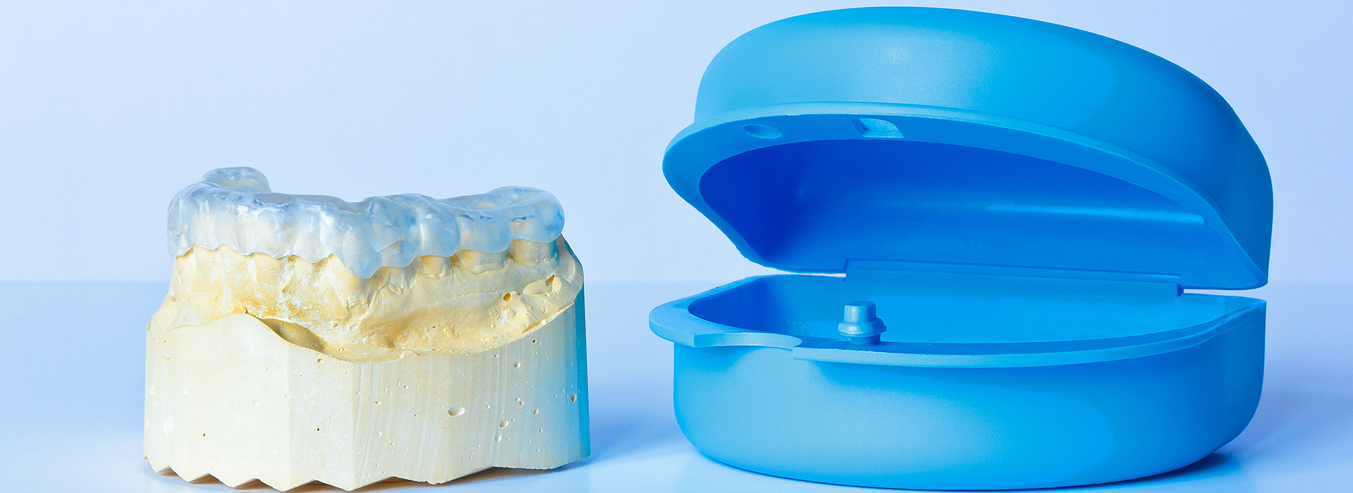 A photograph of a blue dental device next to a yellow dental mold, both placed on a white background.