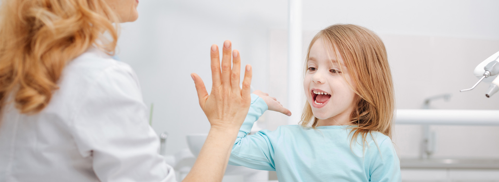 The image is a photograph of a woman and a young girl in an indoor setting, with the woman appearing to be engaged in conversation or interaction with the child.