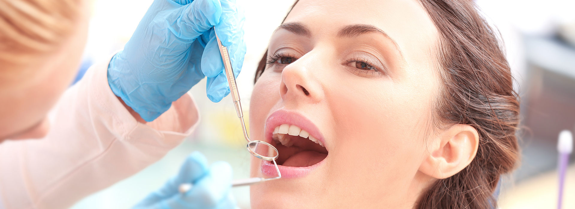 A woman receiving dental treatment, with a dental professional using a drill to work on her teeth.