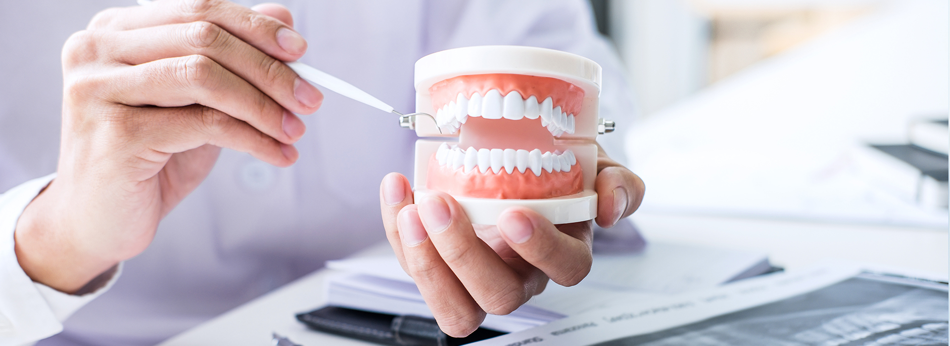 The image shows a person holding a cup with dental implants and a toothbrush, possibly in a dental office setting.