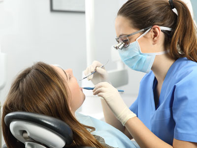 A dental hygienist is performing a cleaning procedure on a patient in a dental office setting.