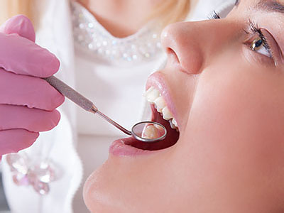 This is an image of a dental professional performing oral care on a patient, with the dentist using a drill and the patient wearing a mouthguard.