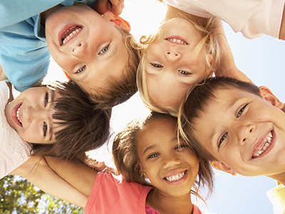 A group of children in a joyful circle, smiling at the camera.